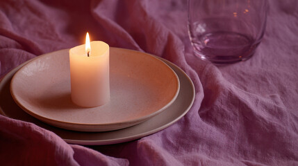 Candle on ceramic plate with purple fabric creates cozy atmosphere