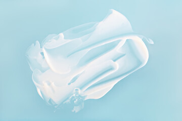 White cream smear on pastel blue background, cream texture captured in soft light for skincare and...