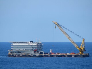 Massive crane vessel dominates the deep blue ocean under a clear sky. A powerful symbol of maritime industry and offshore operations. The vessel is equipped for heavy lifting and transport.