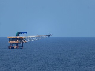 Solitary offshore platform stands tall against a vast, serene blue ocean under a clear sky. A tranquil scene of industrial infrastructure meeting natural beauty.
