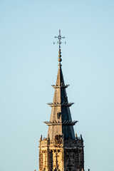 A detailed spire of Toledo Cathedral rises against the clear, cloudless sky in Spain.
