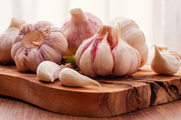 Close-up of several heads and cloves of fresh garlic lying on a wooden chopping board, natural light, selective focus,