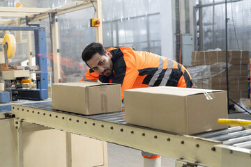 Factory worker inspecting package on conveyor belt