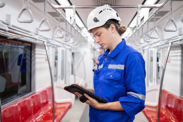 Portrait of young engineer of electric locomotive holding tablet in train