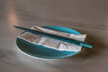 Close-up of a pair of chopsticks and a napkin on a table in a restaurant.