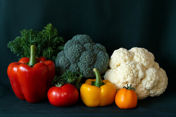 Fresh organic vegetables arrangement: peppers, carrots, tomatoes, broccoli and cauliflower on dark background