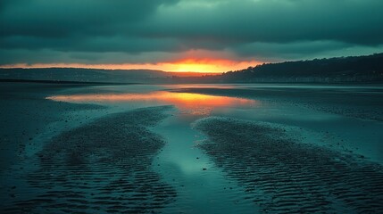 Dramatic sunset over a calm beach.  Sunrise reflected in tranquil water,  dark clouds