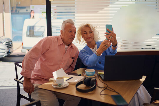 Elderly couple enjoying a coffee while taking a selfie at a cafe