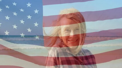 Senior woman on beach smiling, breeze rippling American flag overlay and lifting hair for business - Powered by Adobe