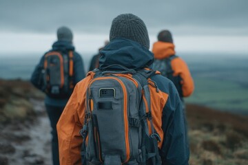 A group of hikers walking in the mountains on a cloudy day, rear view of people with backpacks, going on an adventure, outdoor activities and lifestyle.