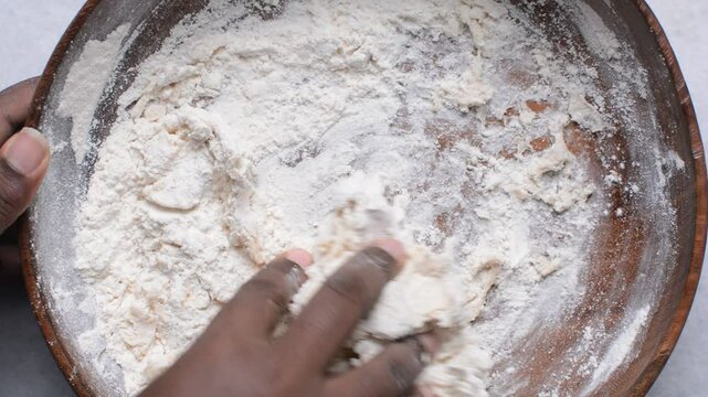 Overhead view of paratha dough being mixed in a wooden bowl, top view of flaky flatbread dough in a wood bowl, process of making paratha