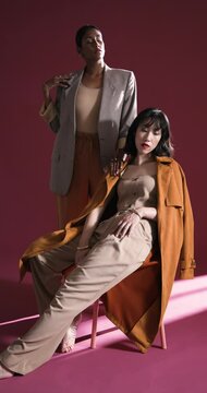 Vertical video: Confident women in stylish outfits posing in studio, showcasing modern fashion