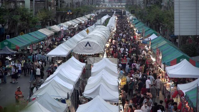 Timelapse of a crowd attending a street market festival in the evening.