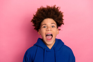 Excited young boy in a blue hoodie smiling with joy against a vibrant pink background, showcasing...