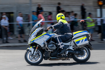 Police Officer Riding a Bright Motorcycle During an Event with Panning Effect and Crowd in Background