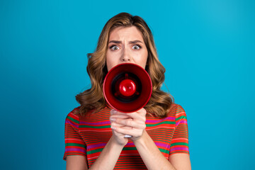 Obraz premium Focused young woman holding a red megaphone against a blue background expressing enthusiasm and energy