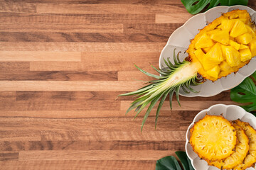 Fresh pineapple chunks served in a pineapple bowl on wooden table background.