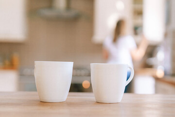 Warm cups on a wooden table in a modern kitchen as a person prepares for their day in a cozy home environment