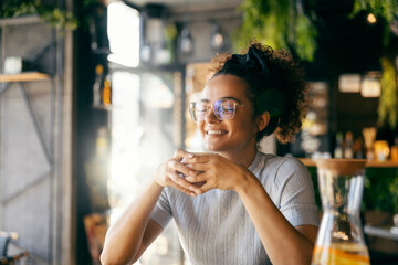 Portrait of multicultural girl enjoying her coffee in cafeteria.