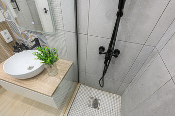 Modern bathroom detail with a stylish sink, black shower fixtures, and textured grey tiles. ...