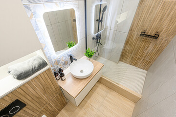 Modern bathroom with a sink, LED mirror, shower, and wooden accents. The design is clean and stylish
