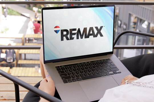 Businesswoman using laptop showing re/max website in outdoor cafe