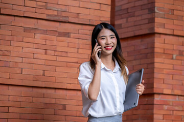 A woman is talking on her cell phone while holding a laptop