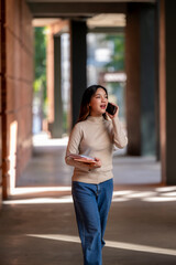 A woman is talking on her cell phone while walking down a hallway