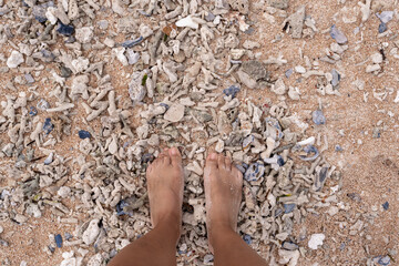Female bare feet stand on a coral-covered beach, connecting with the raw texture of nature. A grounded moment of presence and sensory experience on Gili Islands