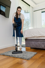Individual cleans bedroom with vacuum cleaner while wearing an apron in a modern home