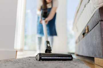 Woman vacuuming carpet in bright room during spring cleaning session at home
