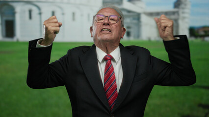 Senior man in a business suit passionately gestures outdoors in front of the pisa tower, capturing...