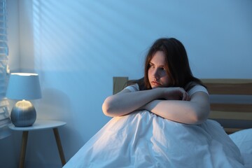 Frustrated young woman suffering from insomnia on bed indoors
