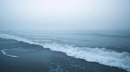 Calm and foggy morning at the sea with gentle waves and a soft breeze, creating a peaceful and reflective ambiance