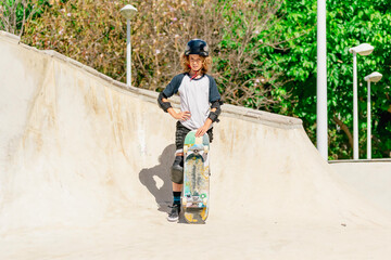 Young boy wearing protective gear posing with skateboard in skatepark © pacoocimage