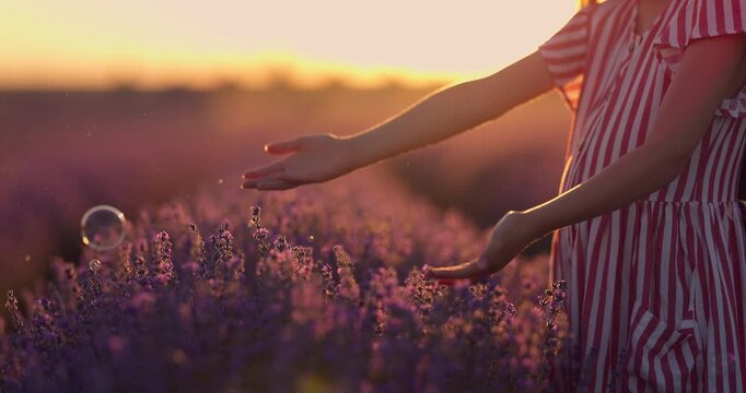 Freedom girl with summer dress and long hair enjoy lavender blossoms in endless blooming field and play with soap bubbles