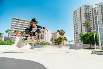 Young boy performing stunt with skateboard in skate park © pacoocimage