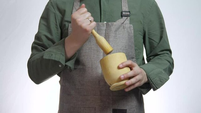 Male hands with a mortar for spices or other products. A white man crushes spices or something else with a mortar.