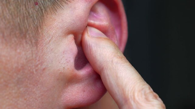 A man cleans his ear.
A man with bad hearing.
Treatment of hearing and ear hygiene.
A man picks his ear with his finger to hear better.
A man touches his ear with his hand