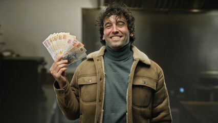 Man smiling while holding turkish lira banknotes in outdoor park setting, showcasing happiness and...