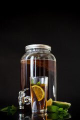 Refreshing kombucha in a glass jar and a glass with lime on a black background