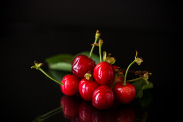 a handful of ripe red cherries on a black background