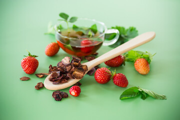 Bright strawberry tea in transparent glassware on a green background