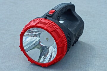 one big powerful new round plastic switched off with white reflector battery operated electric with handle big black flashlight lies on the gray table