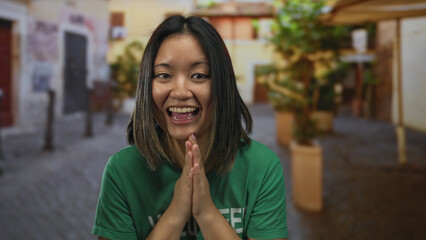 Young woman volunteer claps on a city street wearing a green t-shirt outside, capturing a cheerful...