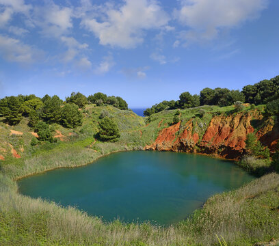 Coastiew of old bauxite quarry in Otranto, Puglia, south Italy. View of aluminium ore quarry and blue lake in bauxite open coast, open pit mine.