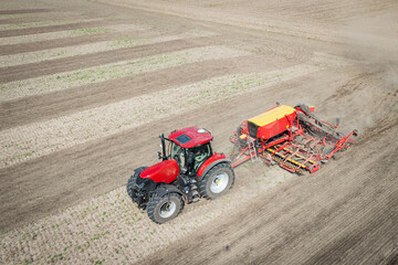Traktor mit moderner Direkt - Sämaschine beim Drillen auf einem staubigen Feld, Luftbild.