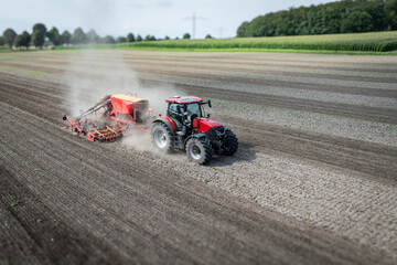 Traktor mit moderner Direkt - Sämaschine beim Drillen auf einem staubigen Feld, Luftbild.