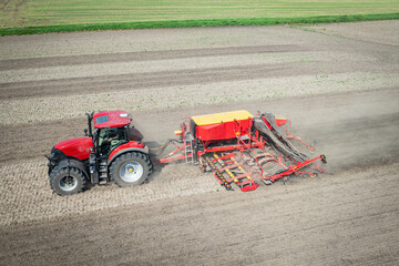 Traktor mit moderner Direkt - Sämaschine beim Drillen auf einem staubigen Feld, Luftbild.