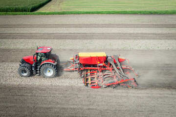 Traktor mit moderner Direkt - Sämaschine beim Drillen auf einem staubigen Feld, Luftbild.